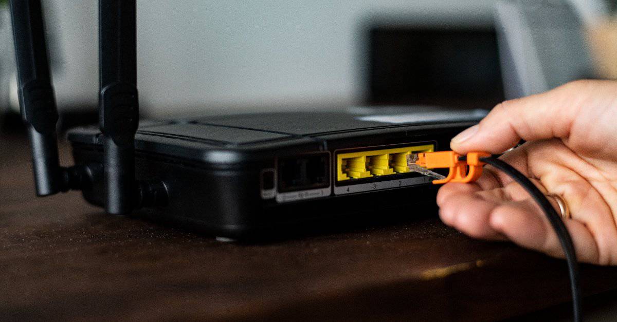 man plugging lan cable to router