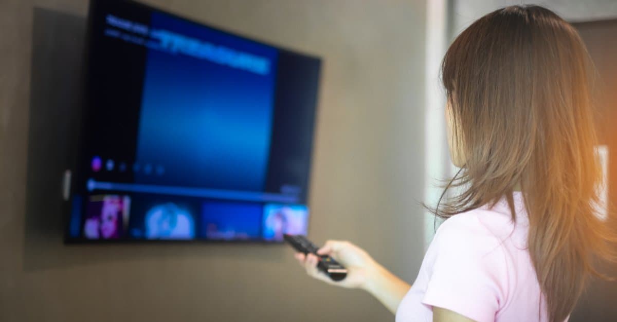 woman using remote in front of her tv